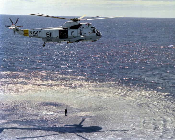 A Sikorsky SH 3H Sea King helicopter lowers an AQS 13 dipping sonar.