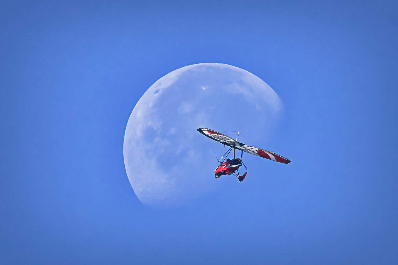 An ultralight aircraft flying in front of the moon at Wiley Slough Washington State