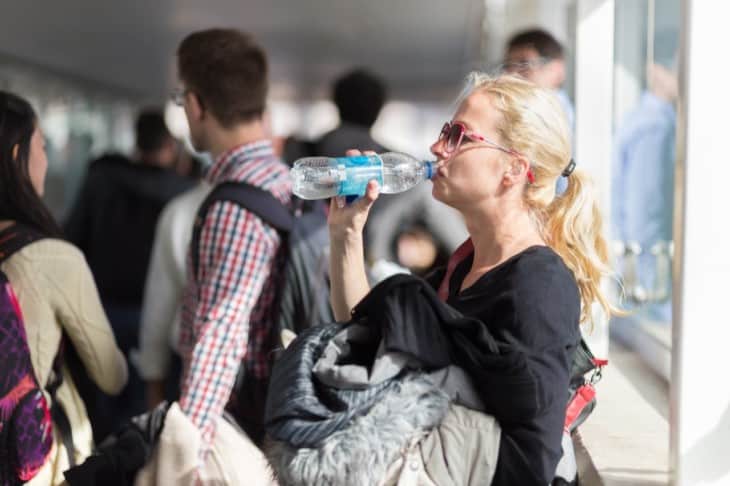 Woman drinking water while queuing to board plane