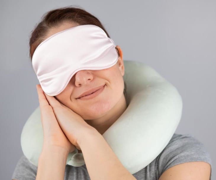 woman with travel pillow and sleeping mask