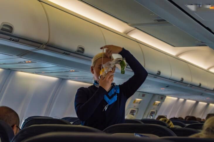 air hostess shows how to use an oxygen mask on board