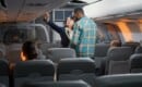 flight attendant helps with carry on luggage during boarding