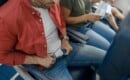 male passenger fastening seat belt on airplane