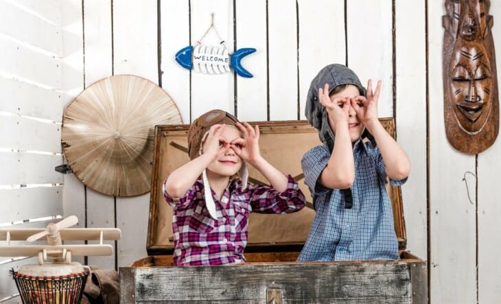 two little kids in pilot hats making glasses with hands