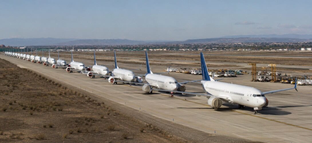 A row of Boeing 737 MAX aircraft parked in a remote storage area