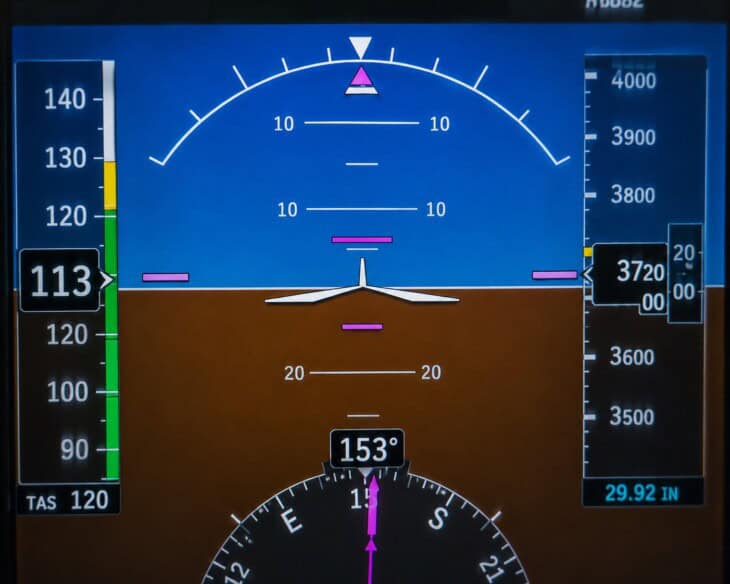 Garmin G1000 primary flight display showing the large artificial horizon with blue sky above, brown earth below, and white horizon line