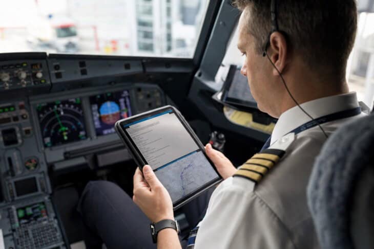 Commercial airline pilot reviewing a flight clearance on an electronic flight bag before departure
