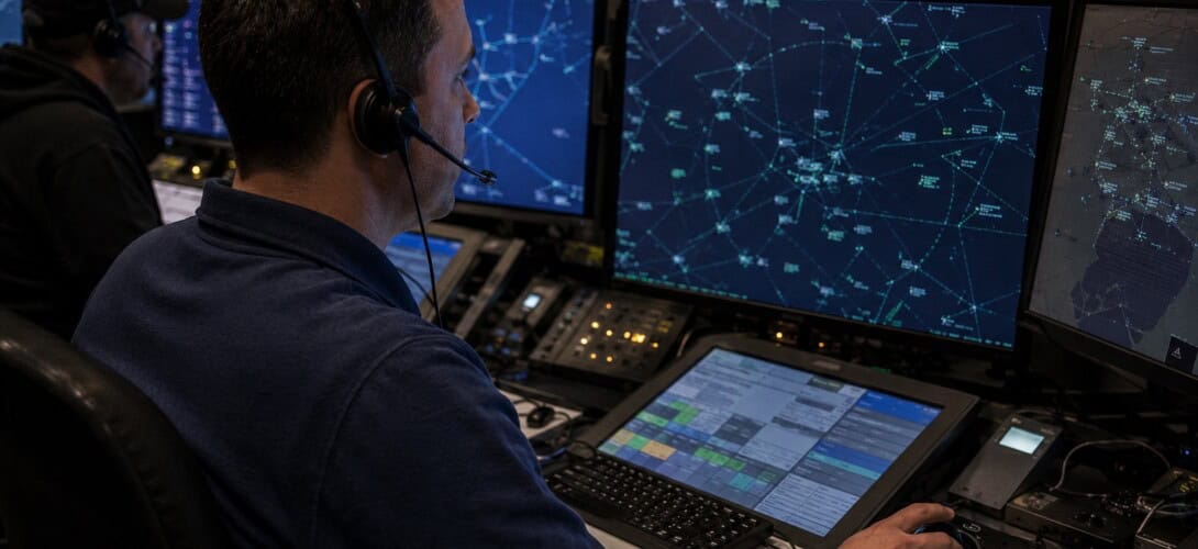 Air traffic controller at a TRACON radar workstation focused on a glowing radar display