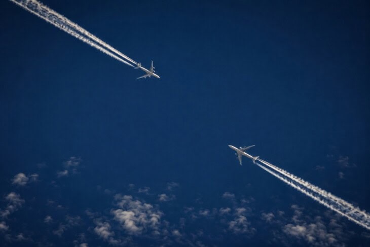 Two commercial aircraft at high cruising altitude with contrails, showing the relative proximity that TCAS is designed to prevent becoming a collision