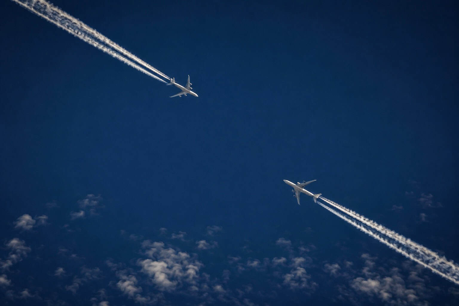 Two commercial aircraft at high cruising altitude with contrails, showing the relative proximity that TCAS is designed to prevent becoming a collision