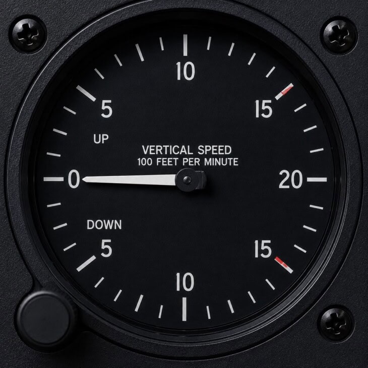 Close-up of a vertical speed indicator dial showing the central zero mark, climb scale above and descent scale below, with needle indicating a gentle climb