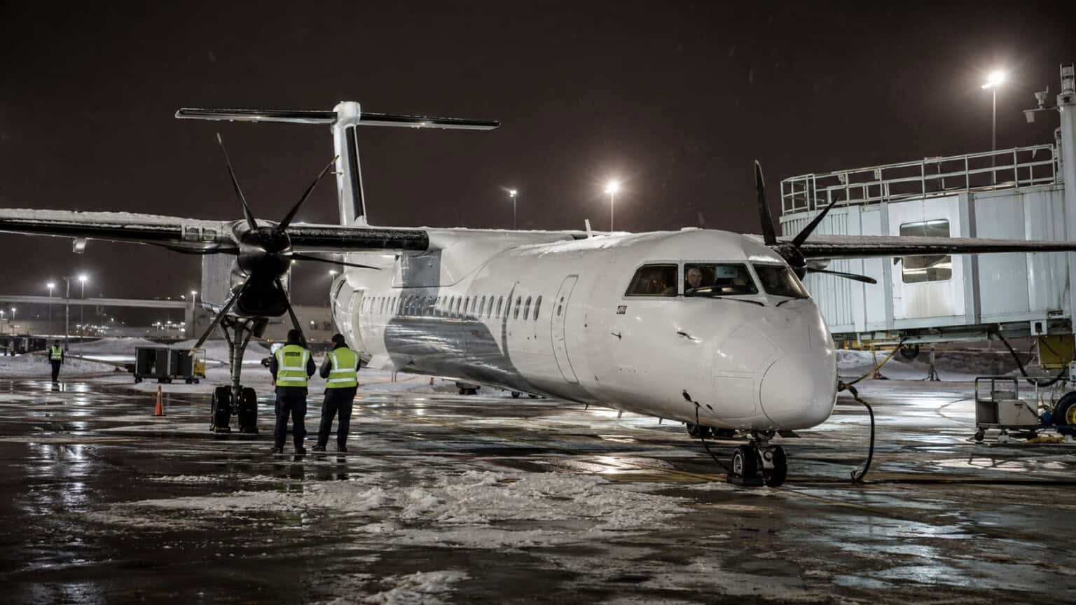 Bombardier Dash 8 Q400 turboprop aircraft parked at a regional airport gate in winter conditions