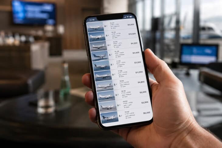 A traveller checking a private jet empty leg listing on a smartphone in an airport lounge