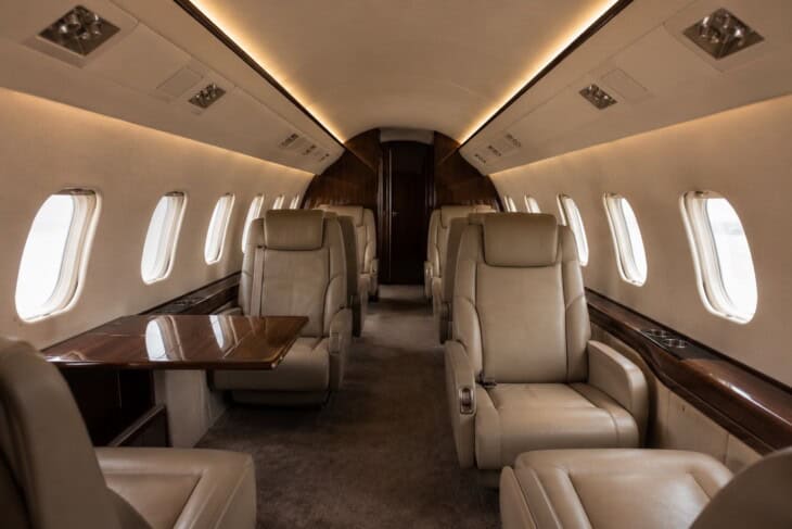 Empty private jet cabin interior with unoccupied leather seats and light through the windows