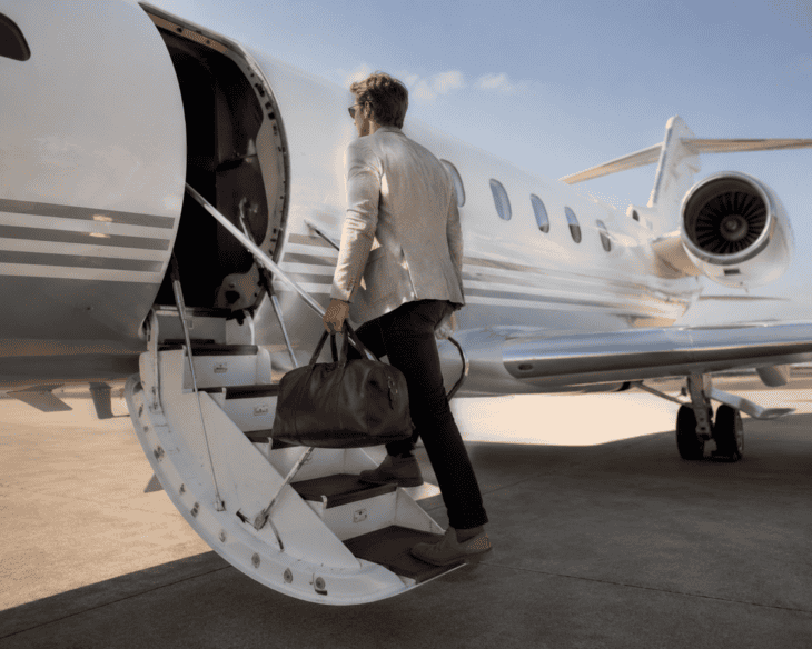 A traveller walking up the air stairs to board a private jet