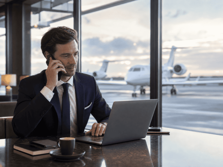 A traveller making a phone call in a private aviation terminal while managing a booking