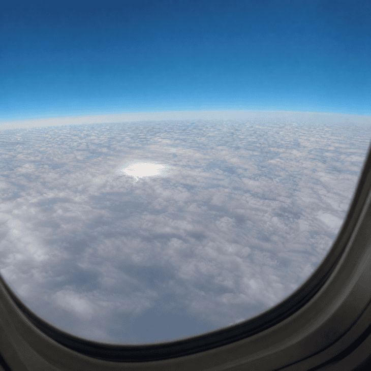 An unbroken layer of white cloud covers the landscape below like a frozen ocean, viewed from an aircraft window at cruise altitude