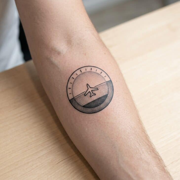 Simplified attitude indicator tattoo on an adult forearm with a clean horizon line and central aircraft symbol
