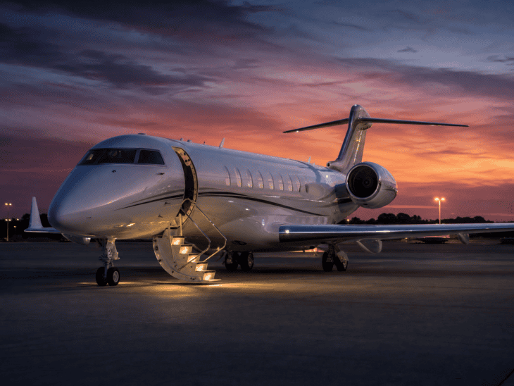 A heavy private jet parked on an FBO ramp at dusk with stairs deployed