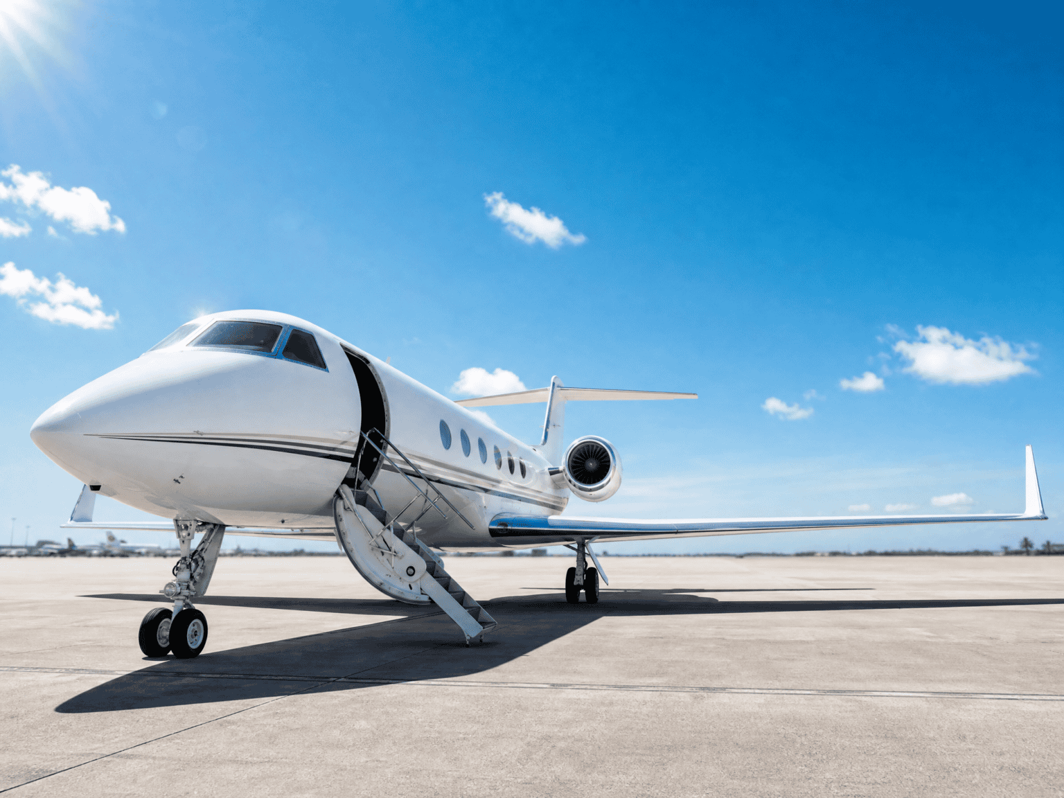A private jet on a sun-drenched FBO ramp in summer with a clear blue sky overhead