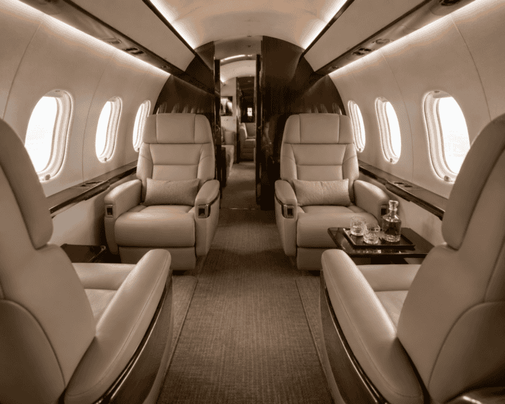 The interior cabin of a private jet with leather seats and a quiet, intimate atmosphere