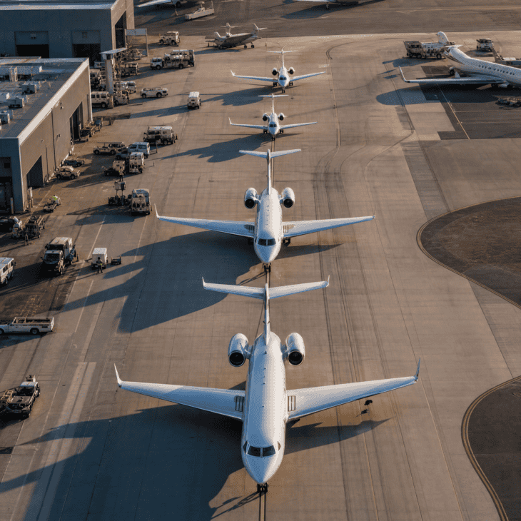 Aerial view of private jets of varying sizes on a busy FBO ramp