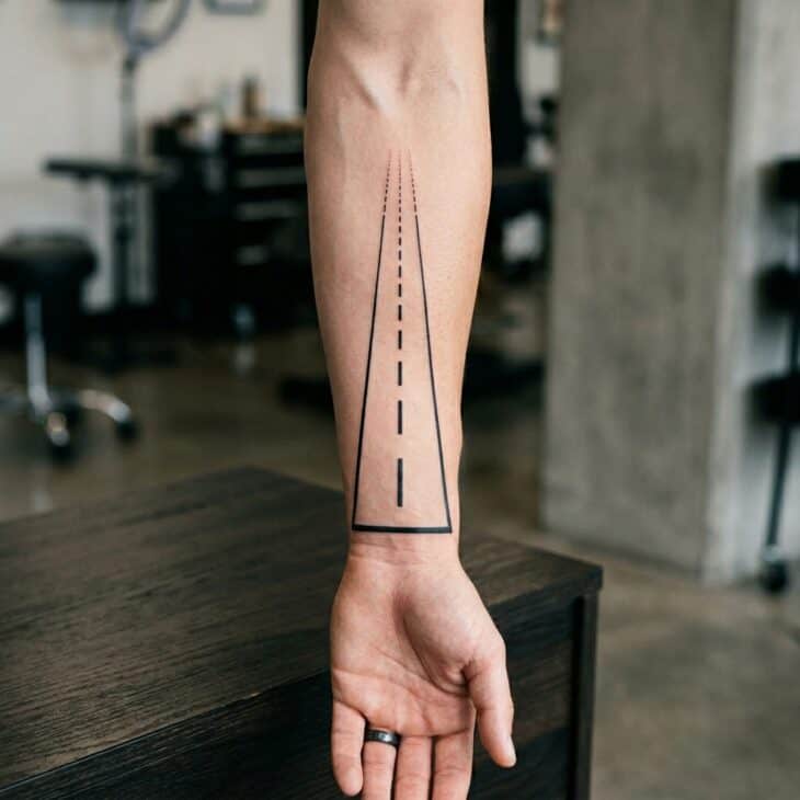 Vertical blackwork runway centerline tattoo along an adult forearm with dashed markings in perspective