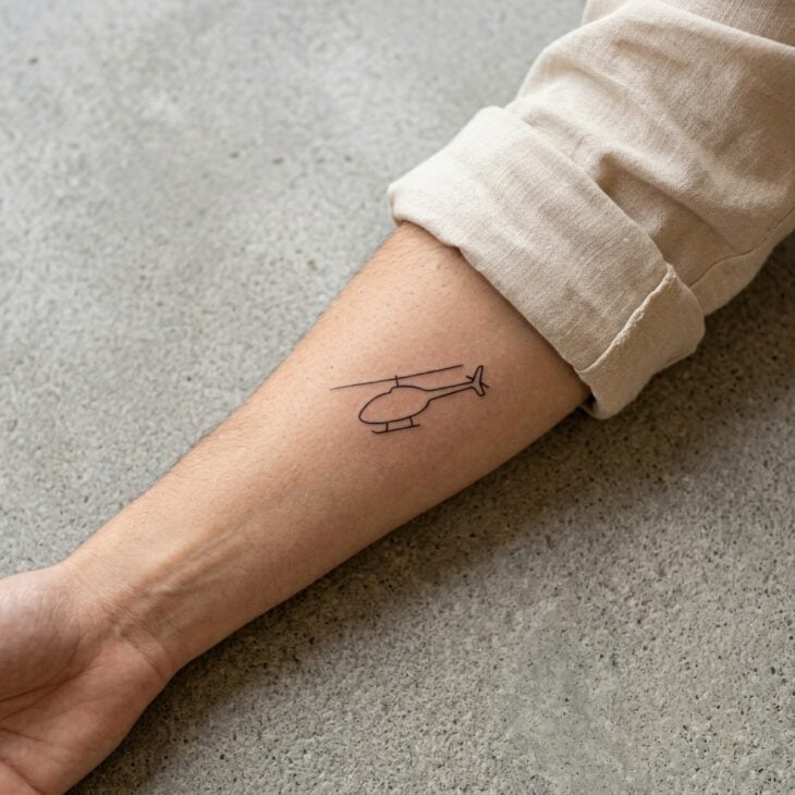 Small generic helicopter silhouette tattoo on an adult forearm with simple rotor line and tail boom