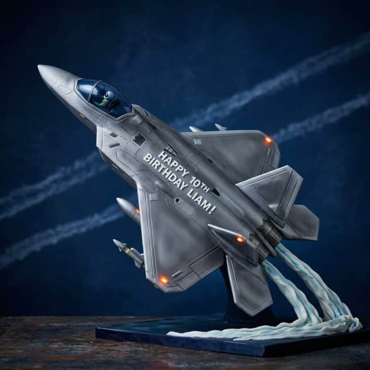 Sleek gray fondant fighter jet cake with swept wings on a dark background