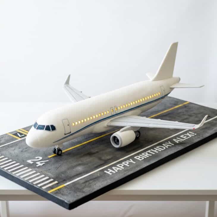 White fondant passenger airliner cake with a row of lit windows