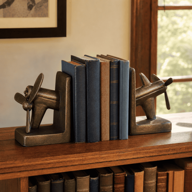 A pair of cast airplane bookends anchors a row of hardcovers.