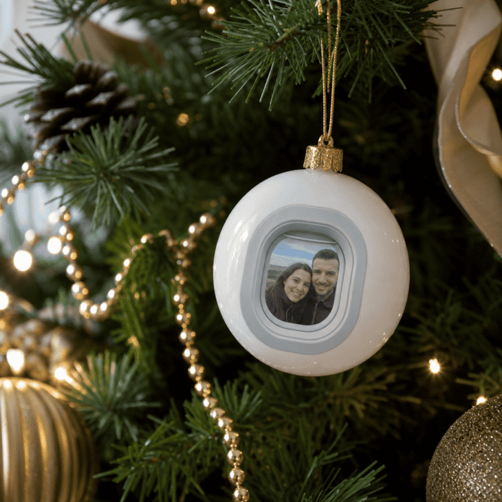 A tree ornament frames a family photo inside a small airplane-window-shaped opening.