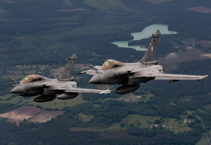 Two French Air and Space Force Rafale fighters flying in close formation over the French countryside