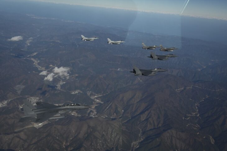 Republic of Korea Air Force F-15K Slam Eagles and KF-16 fighters flying in formation with US Air Force F-16s over mountains