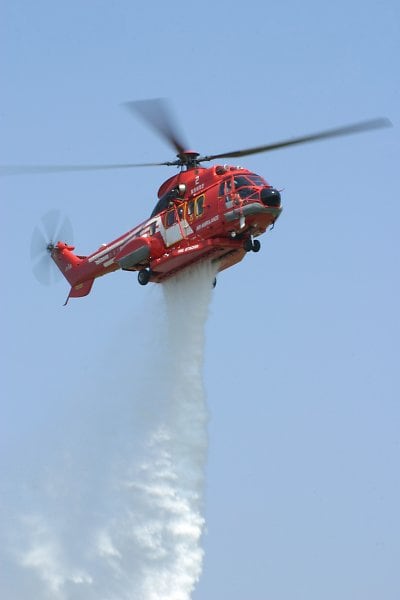 An AS332 firefighting helicopter dropping water