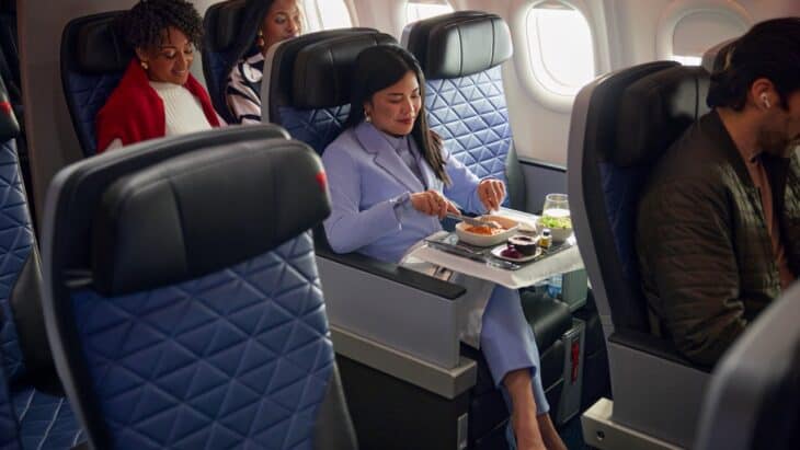 Passengers eating a meal from a full-width tray table in Delta Premium Select