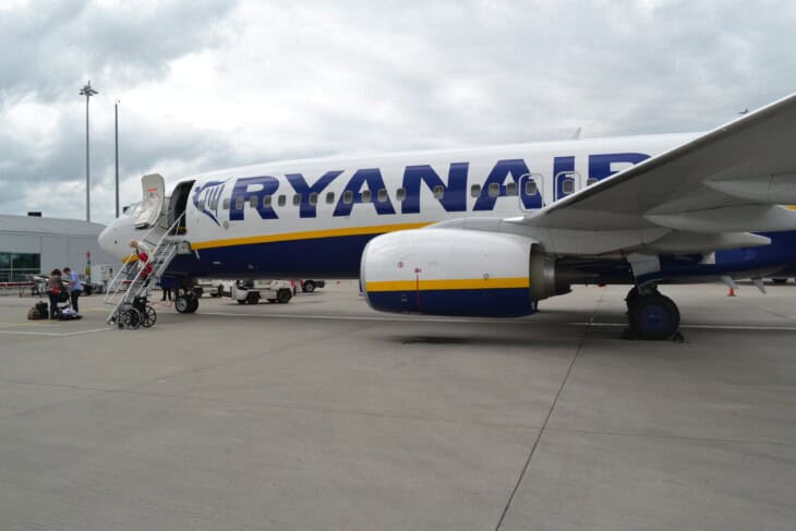 Ryanair Boeing 737-800 parked beside a passenger boarding stair with the Ryanair livery on its fuselage
