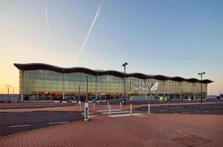 Doncaster Sheffield Airport's wave-roofed terminal at dusk with an empty forecourt