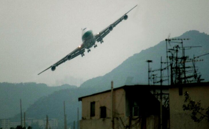 A Boeing 747 banking low over Kowloon rooftops and TV aerials on approach to Kai Tak