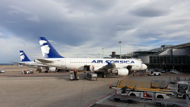 Two Air Corsica Airbus A320s parked at the terminal of Marseille Provence Airport under a cloudy sky