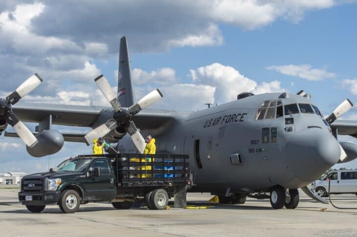 Two 910th Maintenance Squadron technicians transfer insecticide from barrels into the tanks of a C-130 Hercules