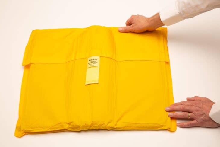A yellow AvSax lithium battery fire containment bag laid flat on a white surface