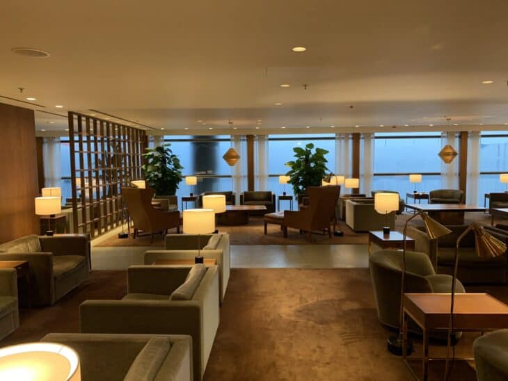 Lounge seating beside tall windows in Cathay Pacific's The Pier lounge at Hong Kong International Airport