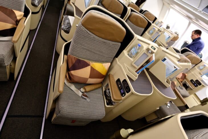 An Etihad Airways business class seat with a patterned cushion and a side console beside the aisle