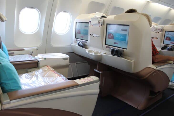 Turkish Airlines business class seats with cream shells, teal pillows and seatback screens by the windows