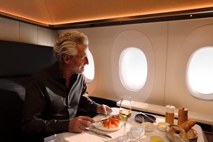 Passenger eating dinner at the table of a SWISS Senses First single suite, with two windows beside him