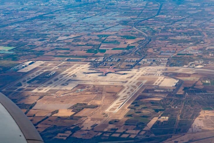 Aerial view of Beijing Daxing International Airport, its runways and pale apron laid out across flat farmland south of Beijing