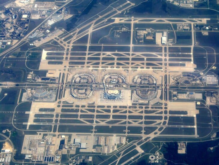 Aerial view of Dallas/Fort Worth International Airport, with its semicircular terminals lined up along the central spine road between parallel runways