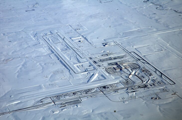Aerial view of Denver International Airport under snow, its runways and taxiways spread across open prairie around the central terminal and concourses
