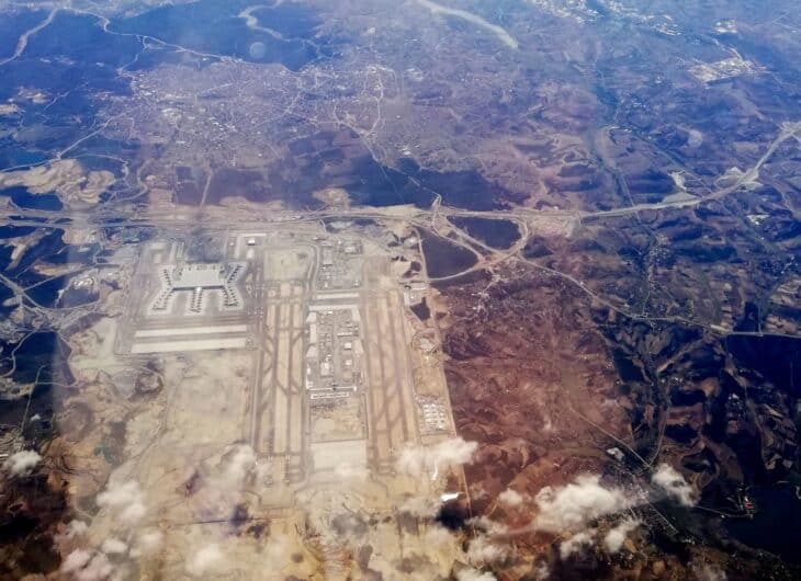 High-altitude aerial view of Istanbul Airport under construction, its parallel runways and main terminal cut into cleared land and forest near the Black Sea coast